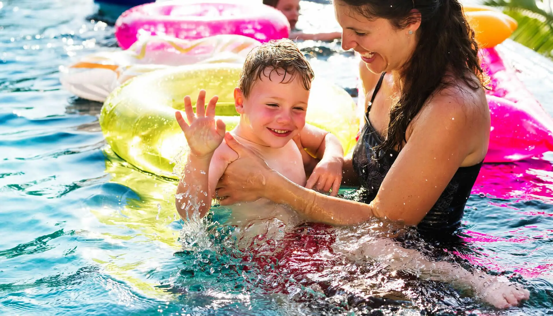 Una mamma con bambino dentro la piscina.