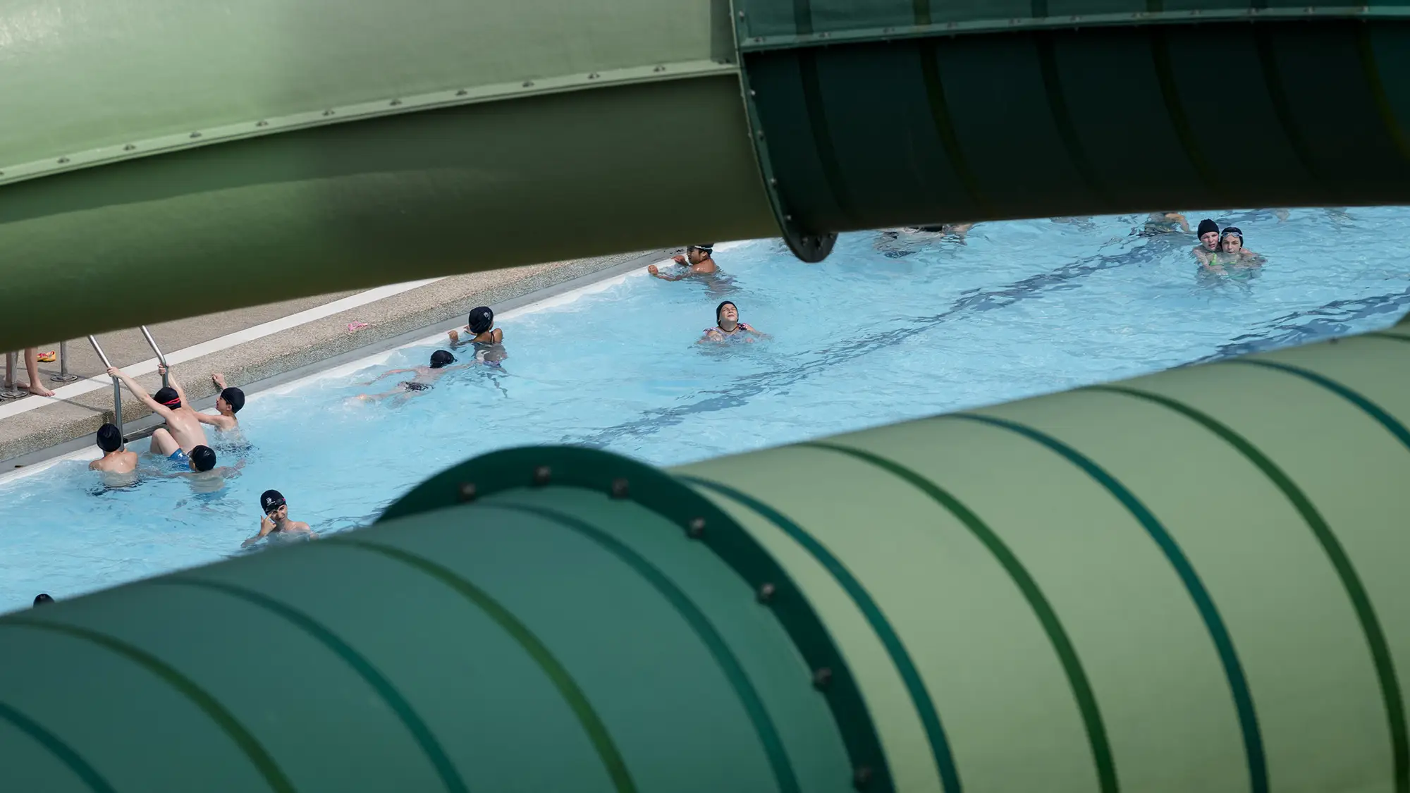 Persone in piscina, in primo piano lo scivolo